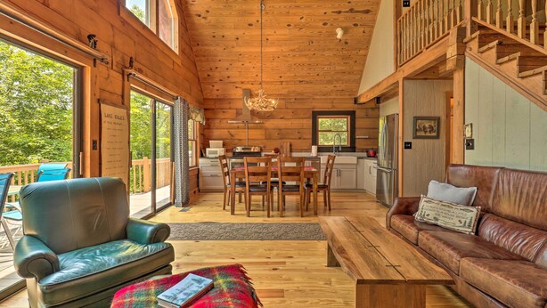 A spacious living area with a wooden ceiling, a dining table with chairs, a leather sofa, and a bench. - Game Room! Lakefront Family Cabin in Landrum (Landrum)