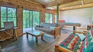A cozy cabin interior with a wooden ceiling, large windows, a sofa, a coffee table, and a pool table. - Game Room! Lakefront Family Cabin in Landrum (Landrum)