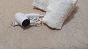 A hairdryer and a white towel on a bed with a patterned bedspread. - St. Peter's Private Room (Roma)