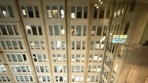 Un edificio de gran altura con varios pisos, una piscina en la azotea y una fachada bien iluminada.