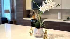 Una cocina moderna con armarios blancos, encimera de mármol y una orquídea en maceta.