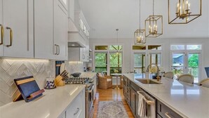 A modern kitchen with white cabinetry, a large island, and pendant lighting. - Hot Tub! Beautiful Mountain Views! Wifi!  Come Visit "Off the Bow"! (Huddleston)