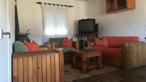 Una sala acogedora con un sofá de madera, un televisor y un armario.