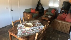 Una sala de estar acogedora con una mesa de madera, sillas, un sofá y un televisor.