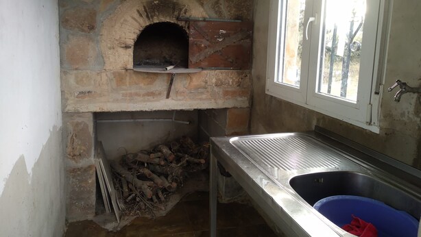Una cocina compacta con horno de piedra, un lavabo y una ventana.
