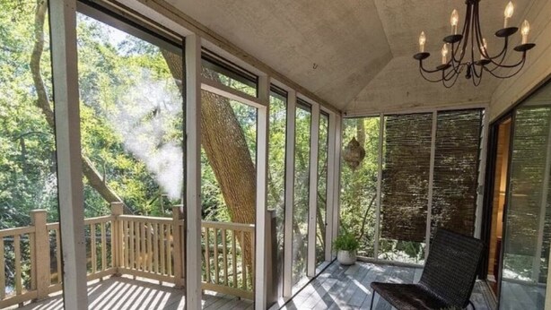 Ein überdachter Außenbereich mit Holzterrasse, einem Stuhl und einem Kronleuchter.