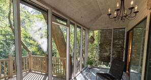 Ein überdachter Außenbereich mit Holzterrasse, einem Stuhl und einem Kronleuchter.