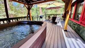 A hot tub on a wooden deck with a view of trees.
