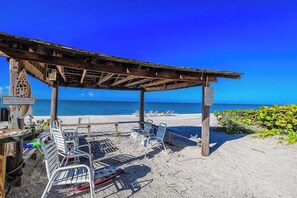 A beachside seating area with metal chairs and a wooden pergola. - Kimball Lodge #244 - Charming 1brm, 1 and a half bath, Beachside condo! (Sanibel)