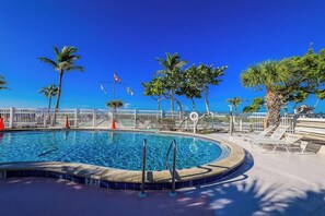 A swimming pool with a white fence, palm trees, and lounge chairs. - Kimball Lodge #244 - Charming 1brm, 1 and a half bath, Beachside condo! (Sanibel)