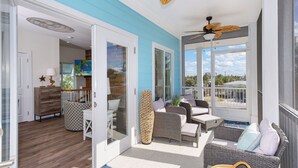 A spacious balcony with wicker furniture, a ceiling fan, and a view of the outdoors. - Bluewater Resort is 2 Properties Sleeping up to 14 (Fort Myers Beach)