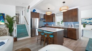 A modern kitchen with a central island, bar stools, stainless steel appliances, and wooden cabinets. - Bluewater Resort is 2 Properties Sleeping up to 14 (Fort Myers Beach)