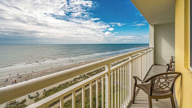 A balcony with a view of the beach and ocean.