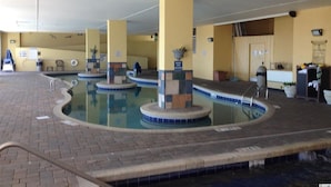 An indoor swimming pool with multiple lanes, a reception area, and a door leading to another room.