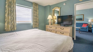 A hotel room with a bed, a TV, a dresser, a mirror, and a blue sofa.