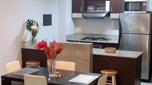 A modern kitchen with a dining area. It includes a dining table with chairs, a kitchen counter, a refrigerator, and a microwave. - modern Loft in city centre with amazing views - in the Financial District -  (Panamá)