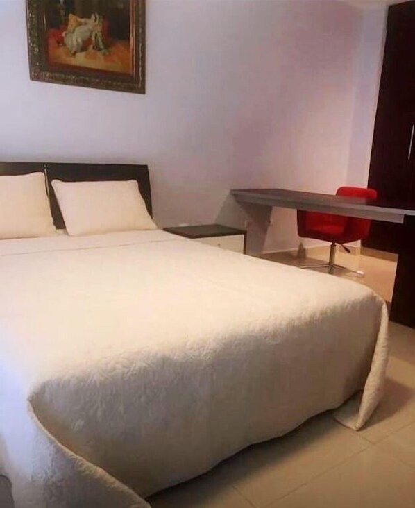 A hotel room with a large bed, a desk, and a red chair. - modern Loft in city centre with amazing views - in the Financial District - (Panamá)