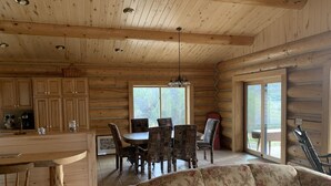 A log cabin interior with a dining area, a sofa, and a kitchen. - Western Slope Mountain Retreat. Privacy, solitude, incredible views (New Castle)