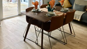 A dining area with a table set for four, a sofa, and a clock on the wall. - Entire Stylish Garden Apartment 2 double ensuite bedrooms sleeps 4 Pet friendly  (Wisbech)