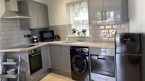 A modern kitchen with grey cabinets, a built-in oven, a microwave, a washing machine, and a refrigerator. - Entire Stylish Garden Apartment 2 double ensuite bedrooms sleeps 4 Pet friendly  (Wisbech)