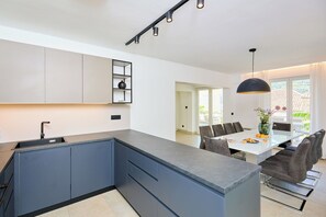 A modern kitchen with a central island, built-in cabinets, and a dining area with a table and chairs.