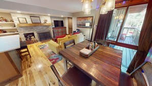 Eine moderne Küche mit Steinrückwand, Holzboden und einem Essbereich mit Holztisch und -stühlen.