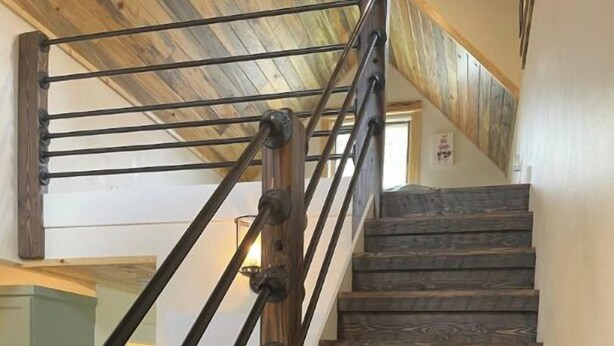 Una scala in legno con ringhiere in metallo che conduce a un piano superiore.