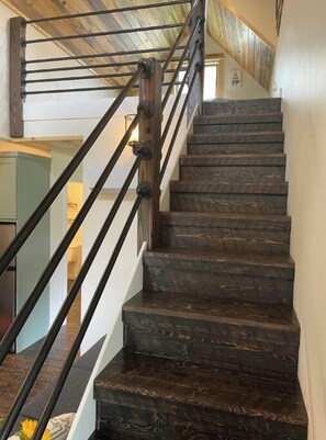 Un escalier en bois avec des rampes en métal, menant à l’étage supérieur.