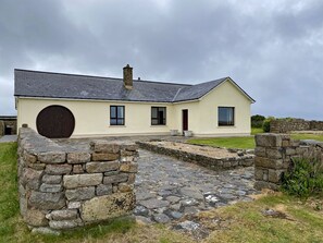 Un bâtiment aux murs de pierre, doté d’une grande porte circulaire, d’un toit en pente et d’un chemin de pierre menant à l’entrée.