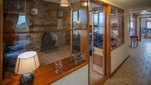 A room with a stone fireplace, wooden furniture, and a view through a glass partition.