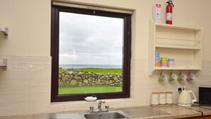 A kitchen with a window, a sink, a coffee maker, and a shelf with jars.