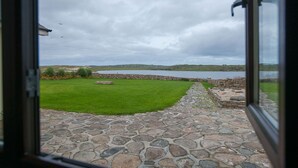 A stone pathway leading to a grassy area with a view of a body of water and distant hills.