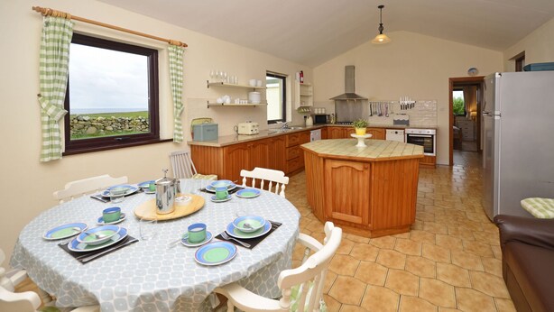 A kitchen with a dining area, wooden cabinets, a central island, and a view of the outdoors.