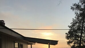 Ein Haus mit Veranda mit Blick auf ein Gewässer bei Sonnenuntergang.