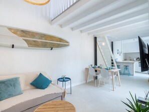 Uma sala de estar moderna com sofá, área de jantar e cozinha.