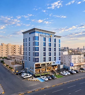 A modern hotel with a prominent entrance, multiple floors, and a parking area. - فندق إمضاء النزيل الفندقية (Jeddah)