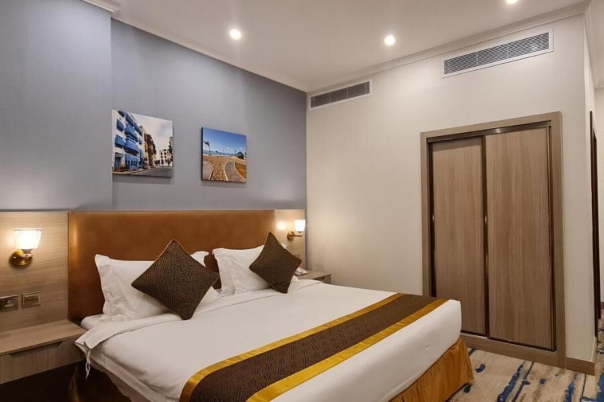 A hotel room with a bed, bedside tables, a wardrobe, and a door.