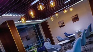 Ein moderner Lounge-Bereich mit blauen Polstersesseln, runden Tischen und Pendelleuchten.