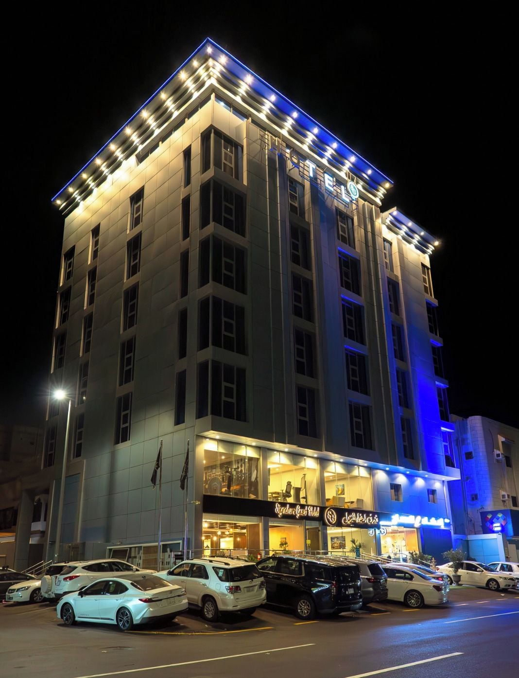 Un hotel de diverses plantes amb un cartell ben visible que diu 'Signature Guest Hotel'.