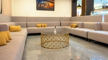Un moderno hall de hotel con un amplio sofá modular, una mesa de centro de vidrio decorativa y una obra de arte enmarcada en la pared.