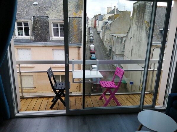 A balcony with a wooden floor, two chairs, and a table. - Apartment near the ocean and beaches (Douarnenez)