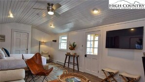 Una sala de estar acogedora con un sofá, una butaca, una mesa de centro y un televisor en la pared.