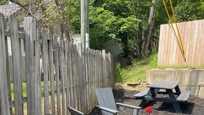 Un patio trasero con una parrilla, mobiliario de exterior y una cerca de madera.
