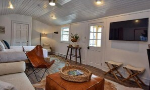 Ein gemütliches Wohnzimmer mit einer Couch, einem Sessel, einem Couchtisch und einem an der Wand befestigten Fernseher.