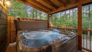 Ein Whirlpool in einer Holzhütte mit Blick auf Bäume.