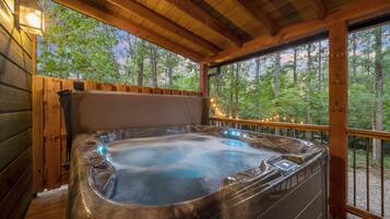 A hot tub in a wooden cabin with a view of trees.