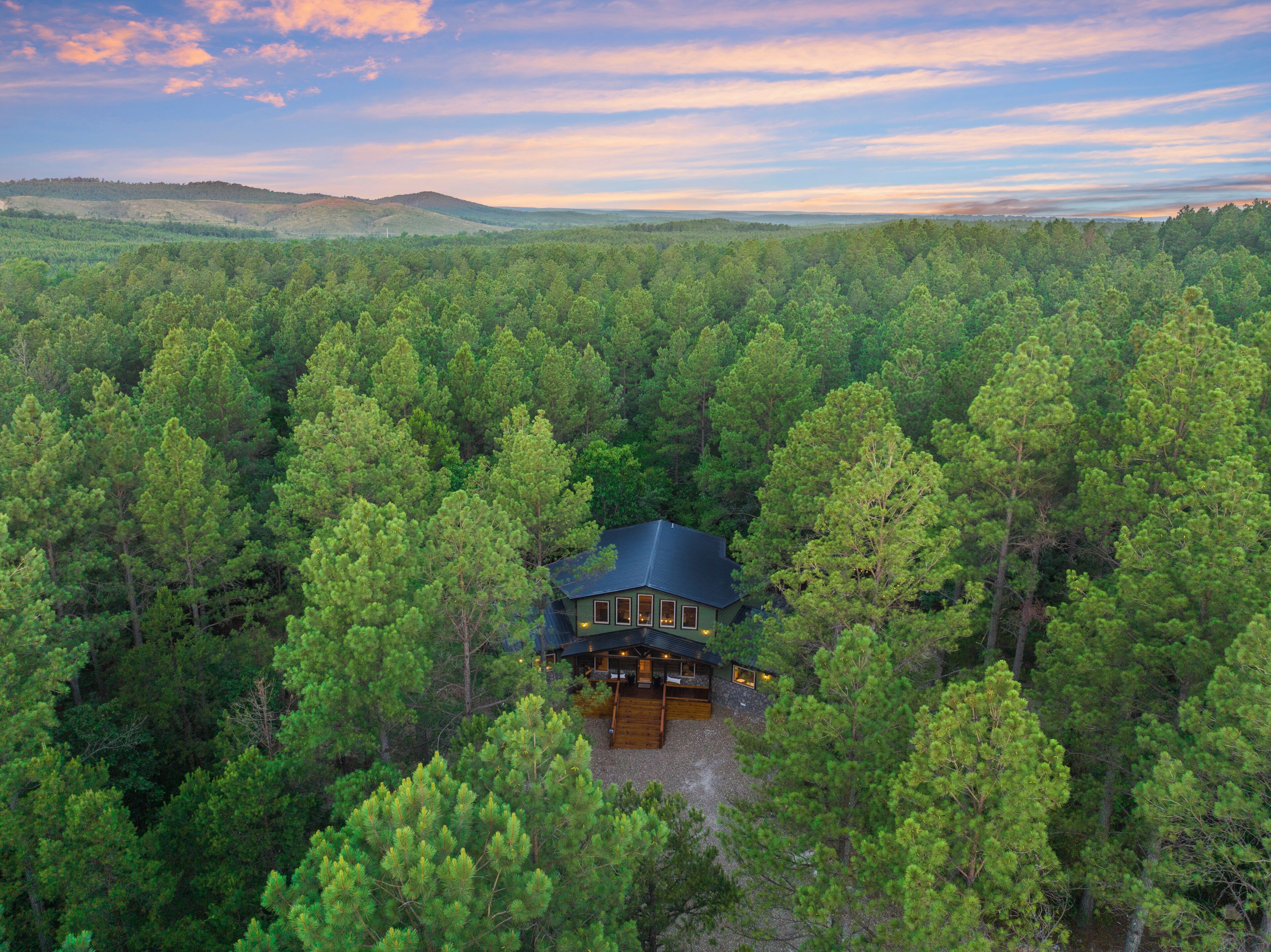 A cabin surrounded by dense forest with a clear view of the surrounding landscape.