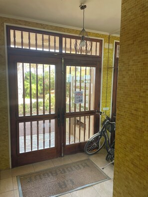 A wooden door with a metal gate, a bicycle, and a doormat. - FRONTLINE APARTMENT WITH OCEAN VIEW (Argelès-sur-Mer)
