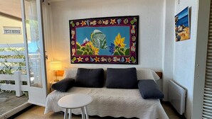 A cozy living room with a sofa, a small round table, and a painting on the wall. - FRONTLINE APARTMENT FACING THE SEA (Argelès-sur-Mer)