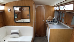 Een compact camperinterieur met een kitchenette, een zithoek en een klein tafeltje.